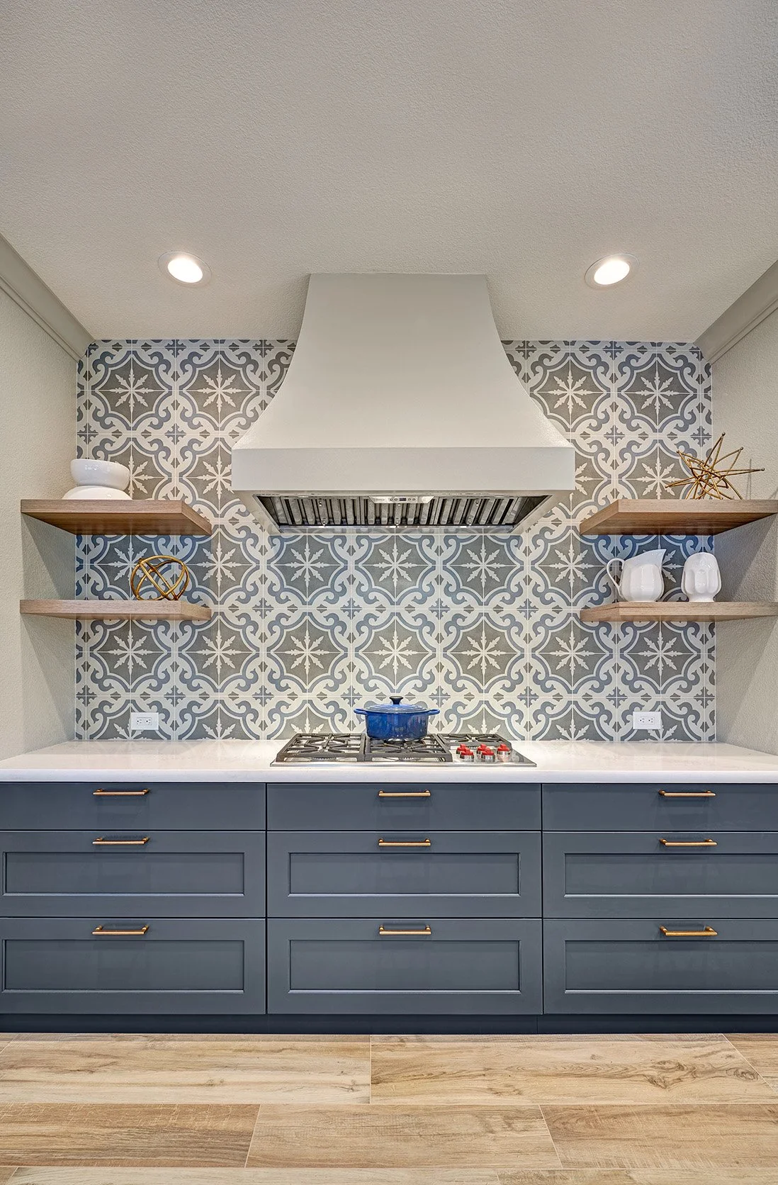 Modern Spanish colonial style kitchen remodel, blue cabinetry, cooktop, curve hood patterned tile splash