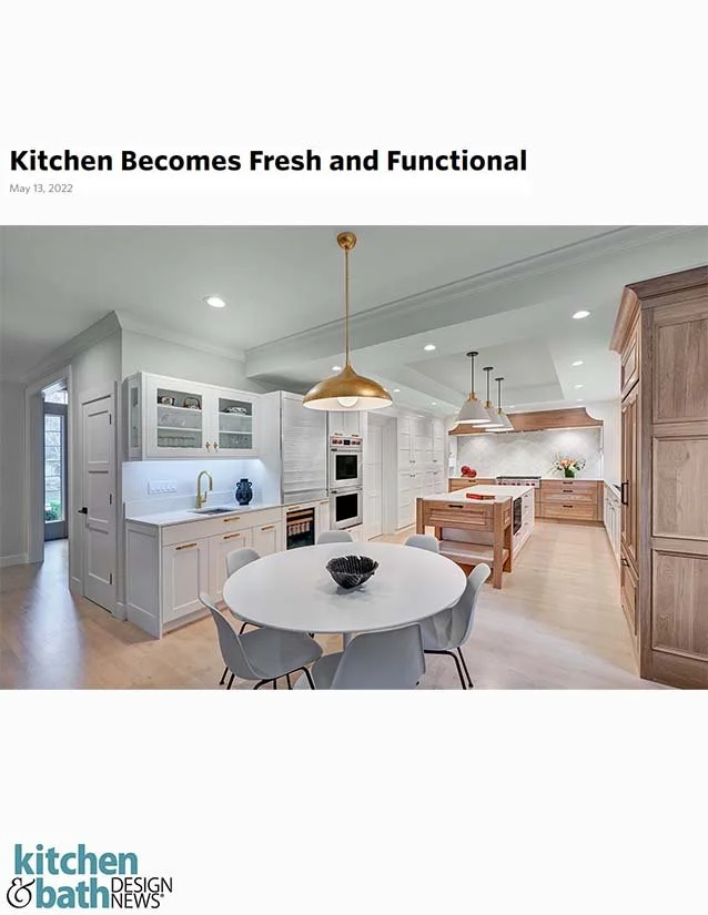 Modern kitchen with white and light wood cabinetry, round dining table with six chairs, gold pendant lights, and stainless steel appliances.