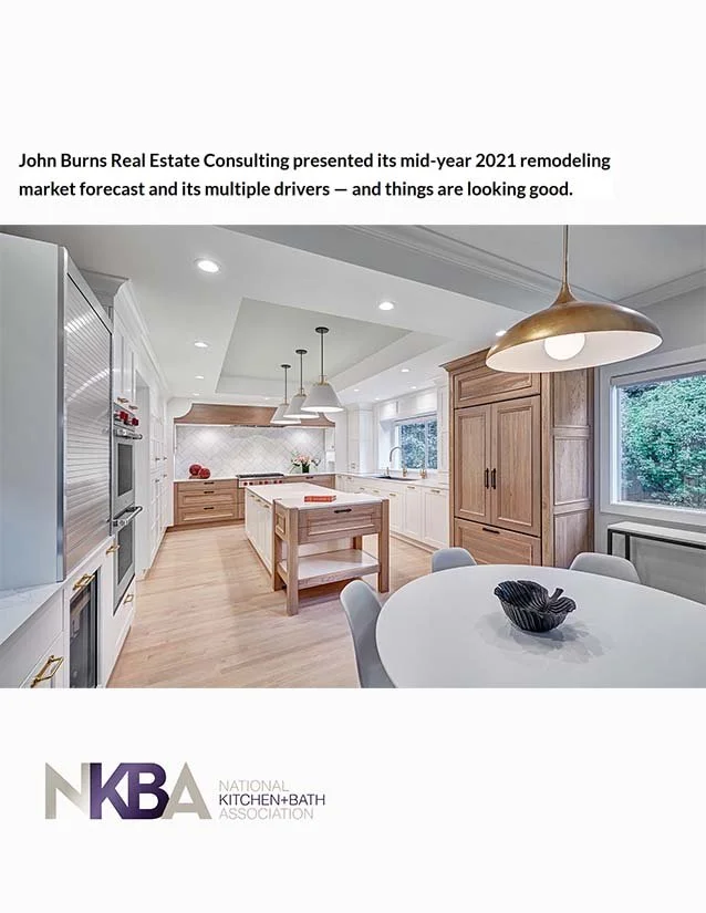 Interior view of a modern, white and wood kitchen with a round dining table and pendant lighting, featured in a report about real estate market forecast.