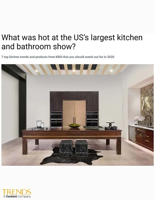 A modern kitchen with a dark wood island, two black wire stools, and minimalist shelving. The ceiling has a striped pattern, and there is a gold and white abstract wall art on the right wall.