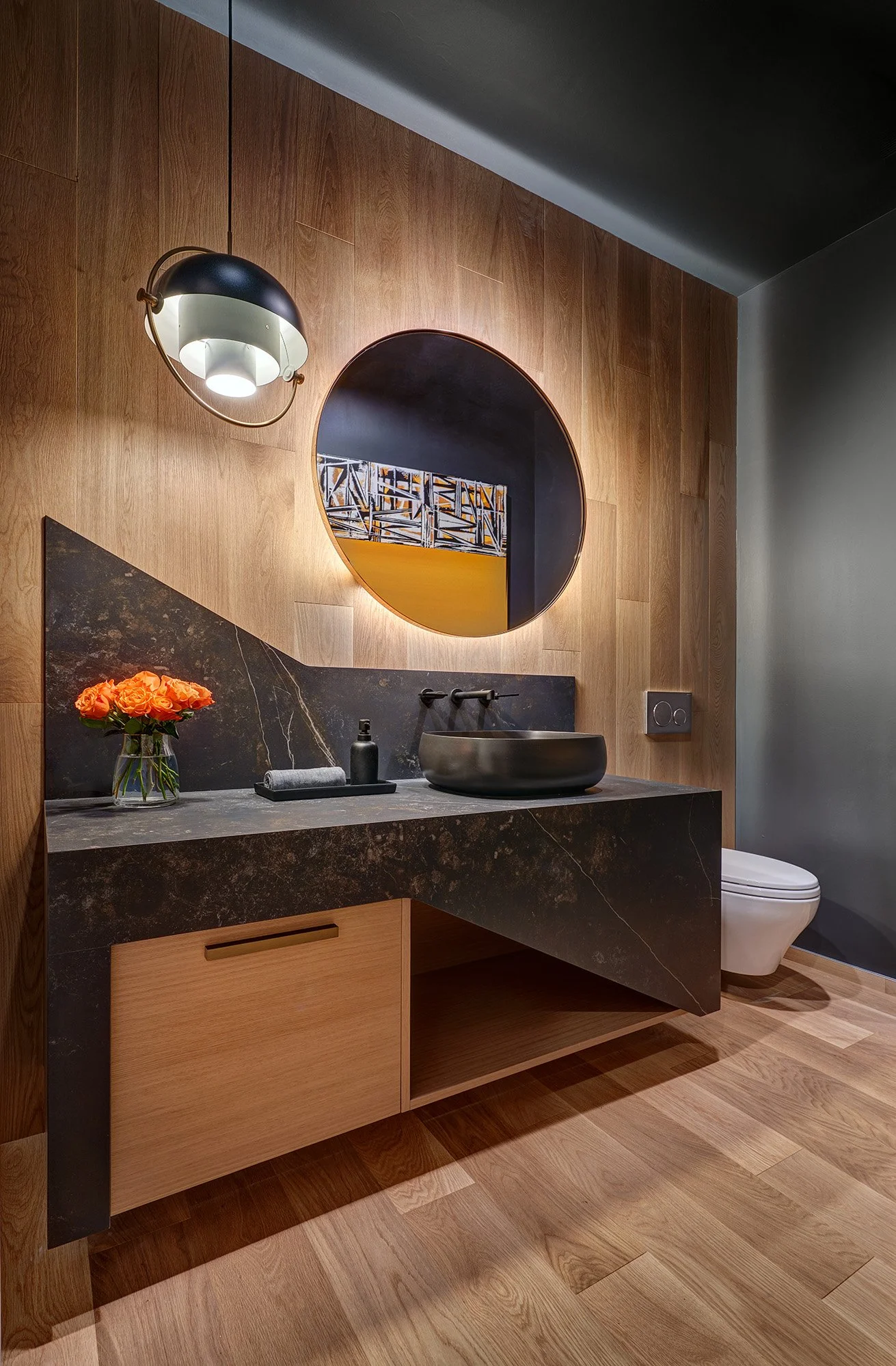 Modern whole home remodel, European cabinetry vanity, angled Dekton countertop, splash + waterfall, wall hung toilet, round backlit mirror