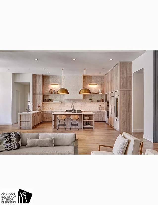 Modern kitchen with wooden cabinetry, white countertops, two gold pendant lights above island, and two bar stools in a contemporary open-concept living space.