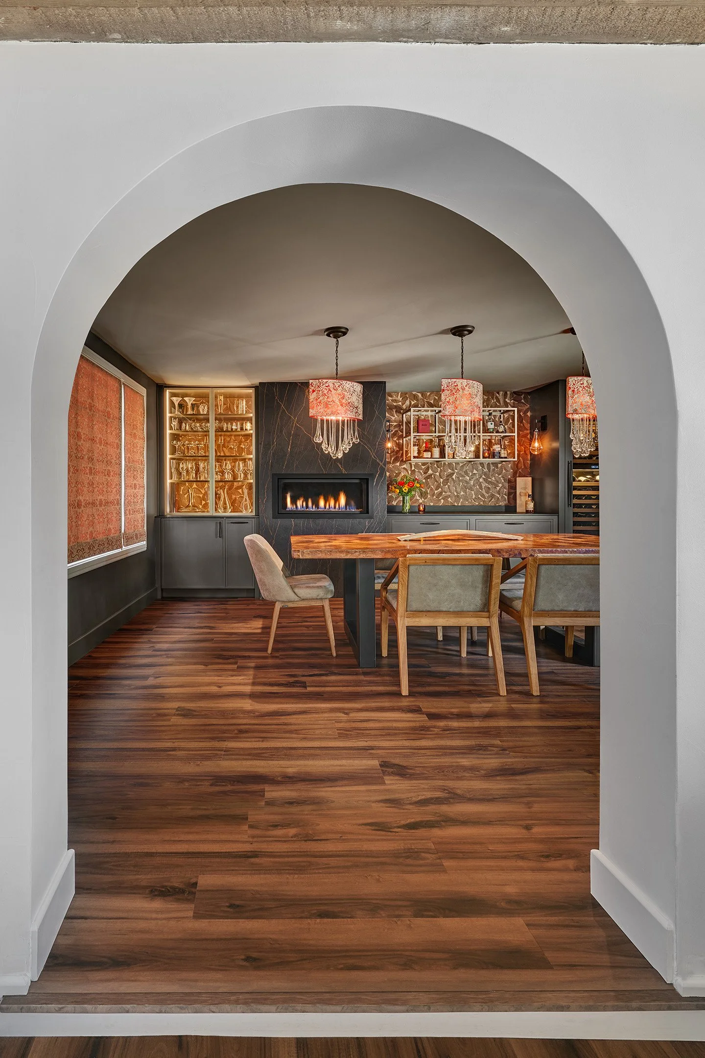 Arch doorway to remodeled dining room, European cabinetry, glass front internally lit display cabinet, paneled wine refrigerator, linear fireplace