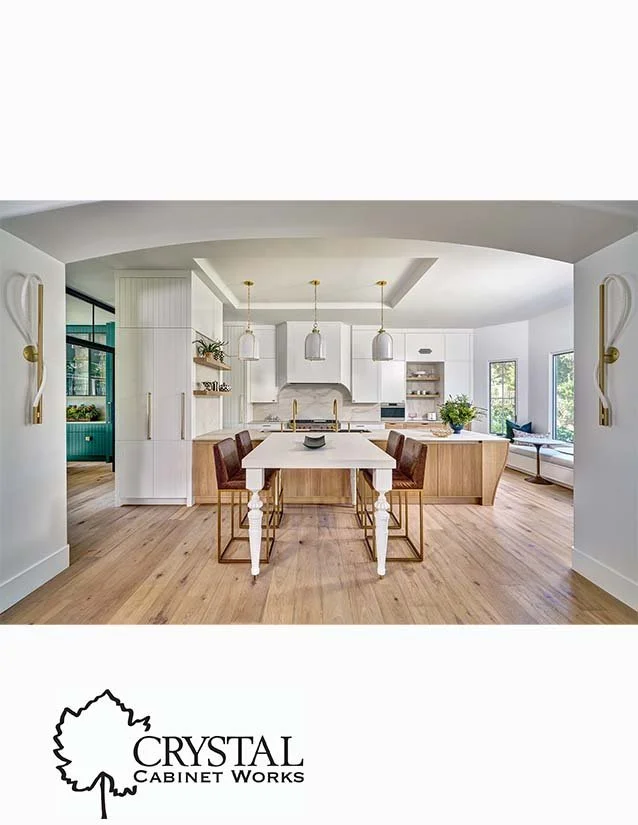 Modern open-concept kitchen with white cabinets, wooden island, pendant lighting, and large windows.