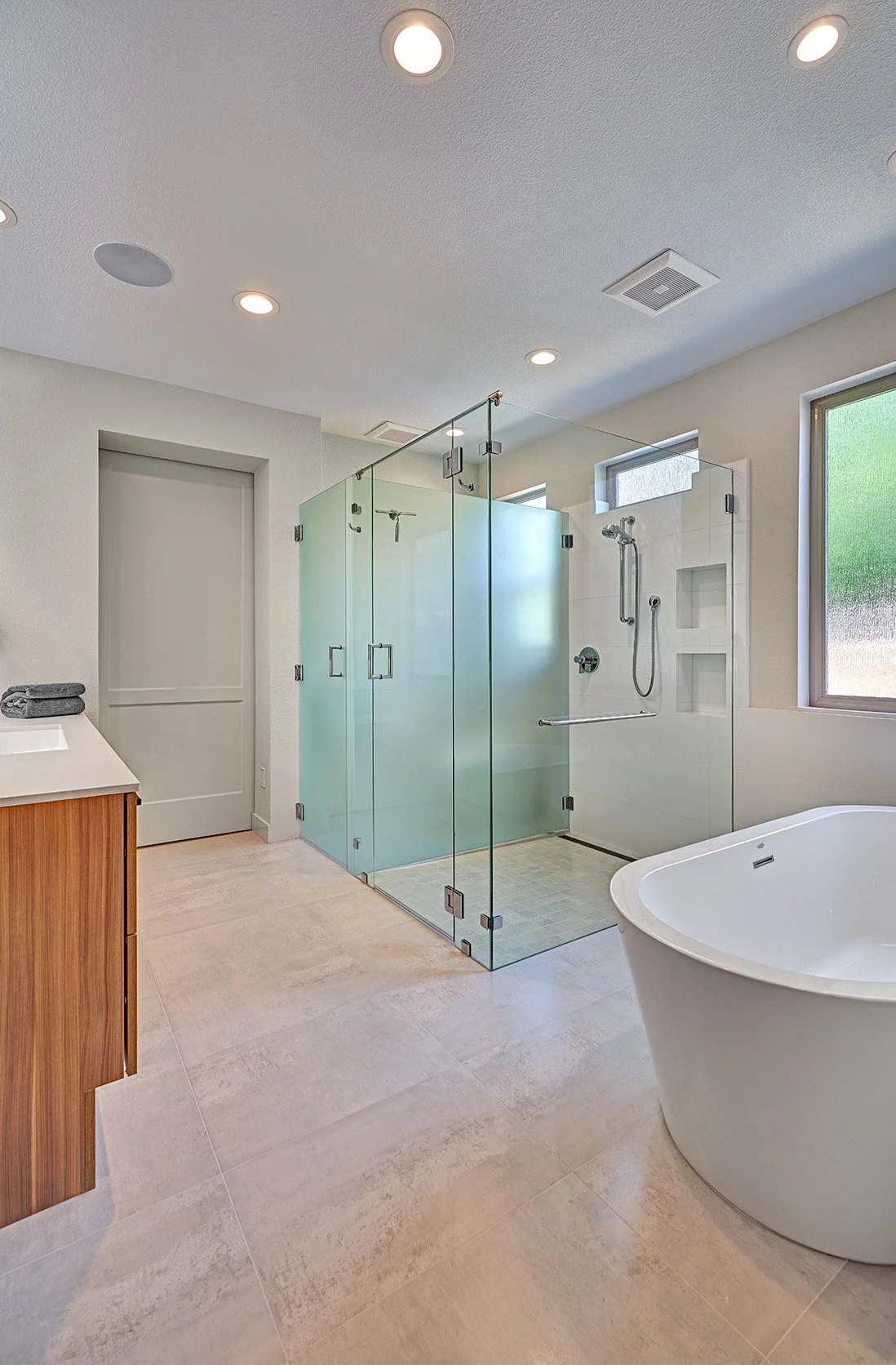Modern primary bath remodel, European cabinetry, glass shower and toilet enclosures, freestanding tub