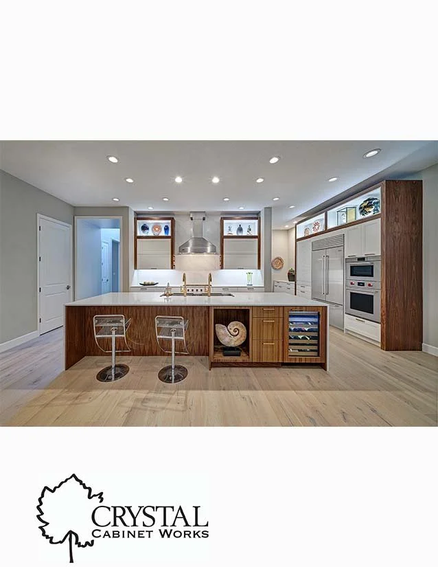 Modern kitchen with white cabinets, wooden accents, stainless steel appliances, and a large island with two bar stools.