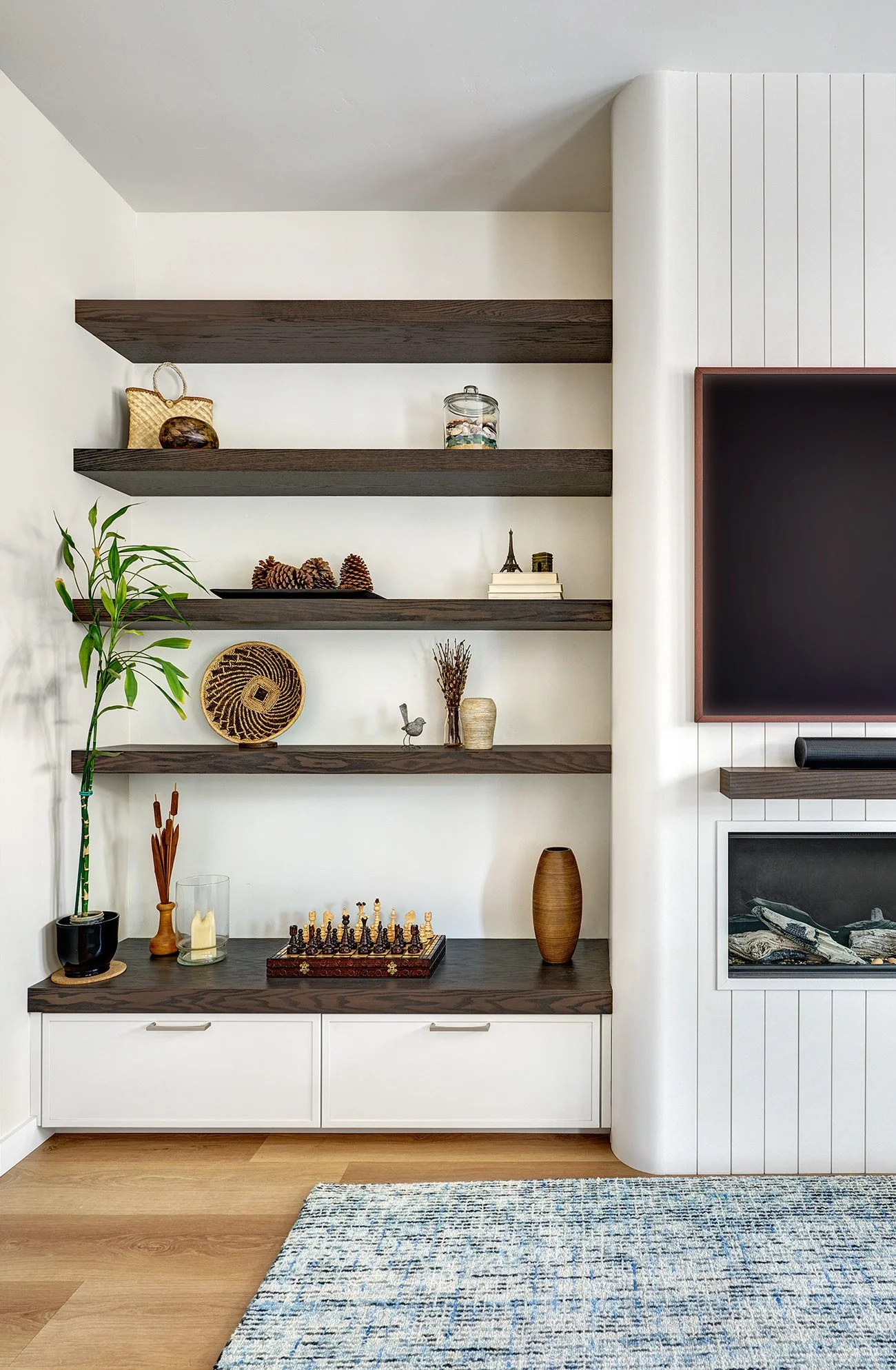 Living room cabinetry display with wood floating shelves, drawers and custom kerf cut fireplace surround.