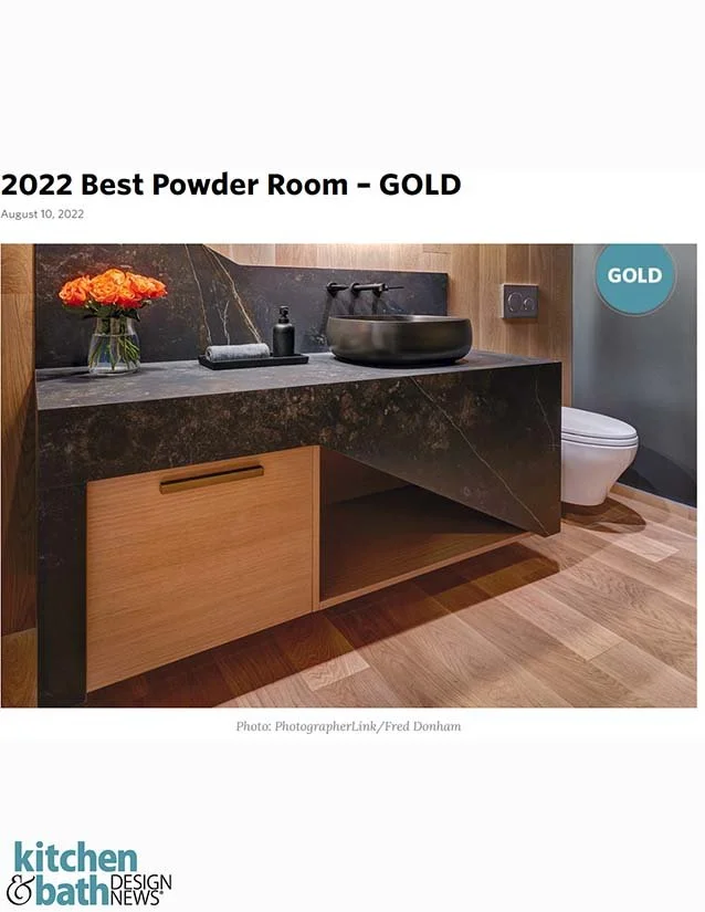 Modern bathroom with black marble vanity, black vessel sink, wooden cabinet, flowers, and toilet, labeled as 2022 best powder room gold.