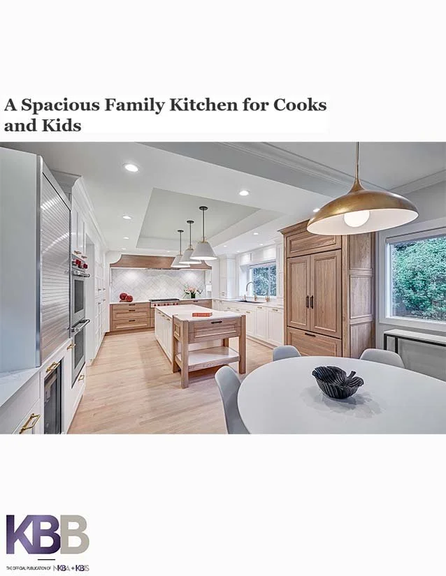 Bright, spacious kitchen with light wood cabinets and modern appliances, including a central island, round dining table with chairs, and a window with a view of greenery.