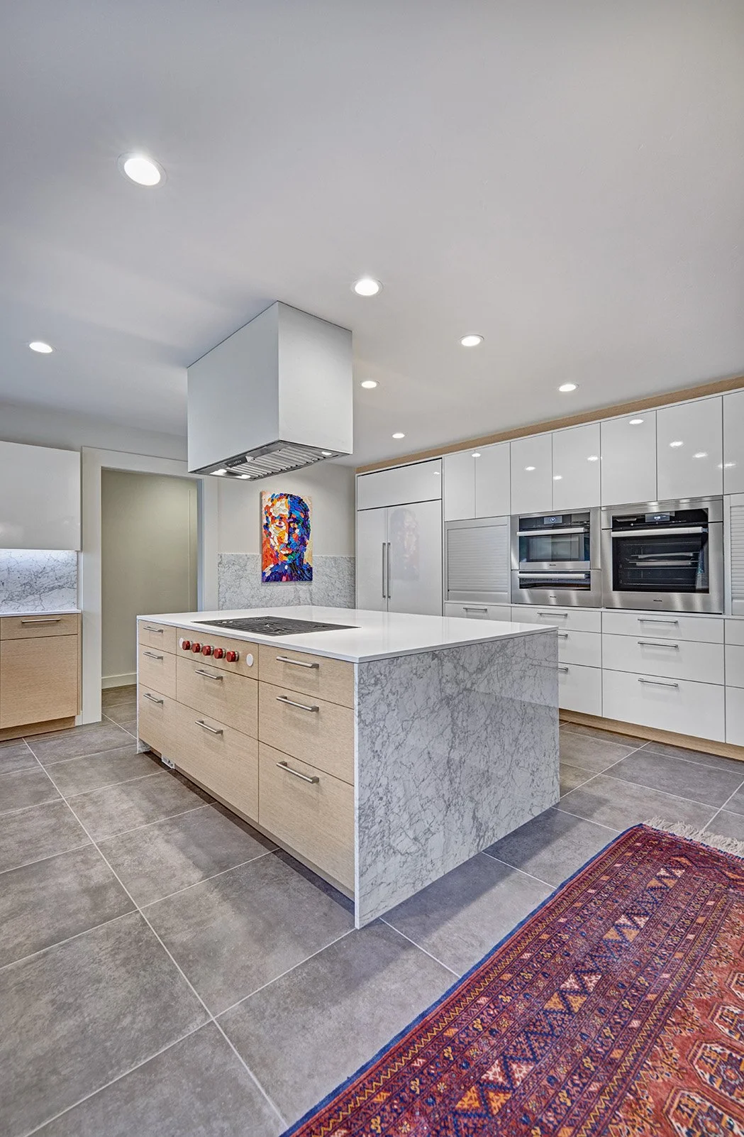 Modern kitchen remodel, wood wrapped white tall cabinet wall, appliance garage, stone waterfall island, flush cooktop