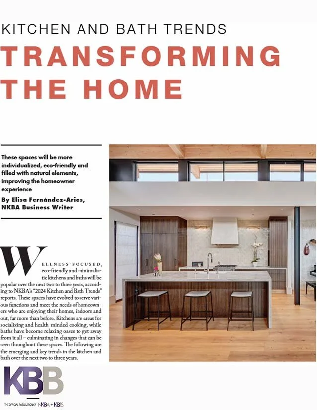 Page from a magazine with the headline 'Transforming the Home' in large red letters, featuring a modern kitchen with a center island, wooden floors, dark cabinetry, and large windows.